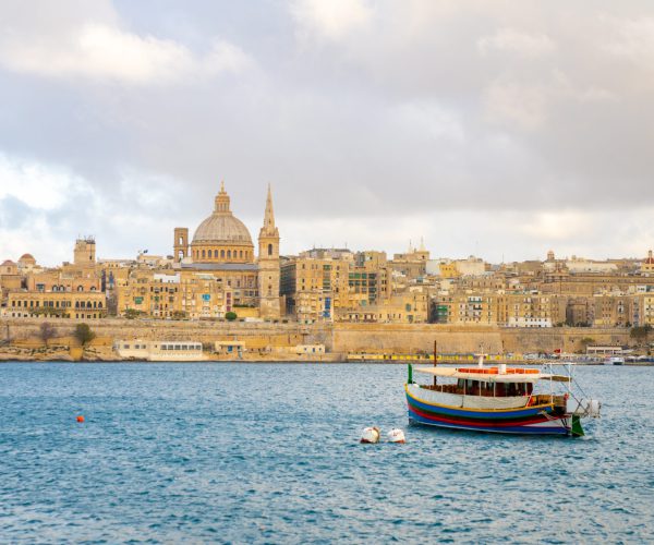 A beautiful sunset view of historic sites by the river in Valletta, Malta