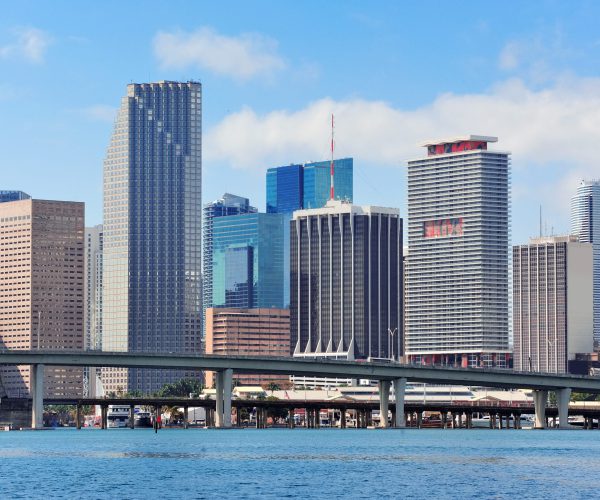 Miami skyscrapers with bridge over sea in the day.