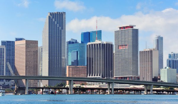 Miami skyscrapers with bridge over sea in the day.