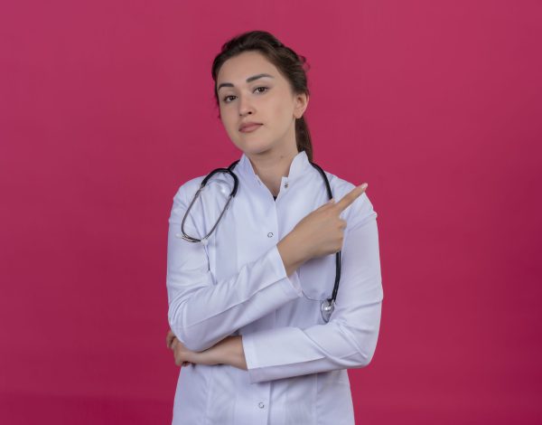 thinking doctor young girl wearing medical gown and stethoscope points to side on isoleted red background